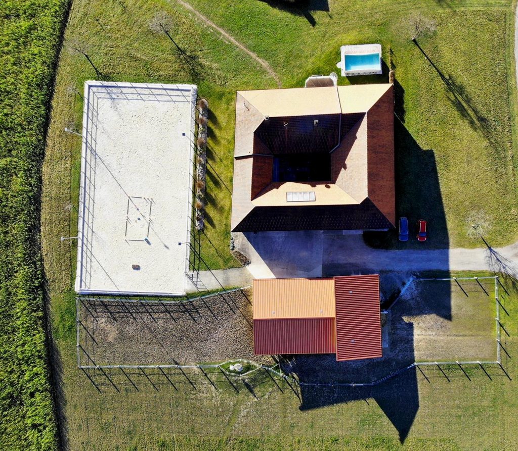 Charlie's Ranch aus der Vogelperspektive mit Sicht auf Wohngebäude, Reitplatz, Stall und Koppel